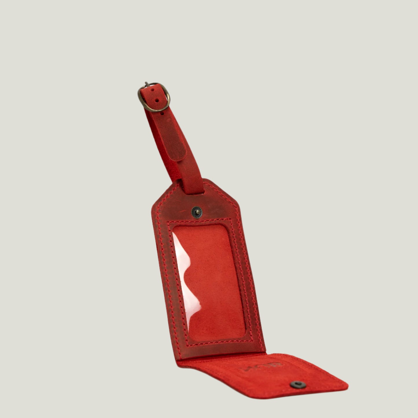 Close-up of a handcrafted Bond Leather Luggage Tag by Atelier PEGAI, featuring premium suede, antique brass hardware, and a personalized fire-branded initial.