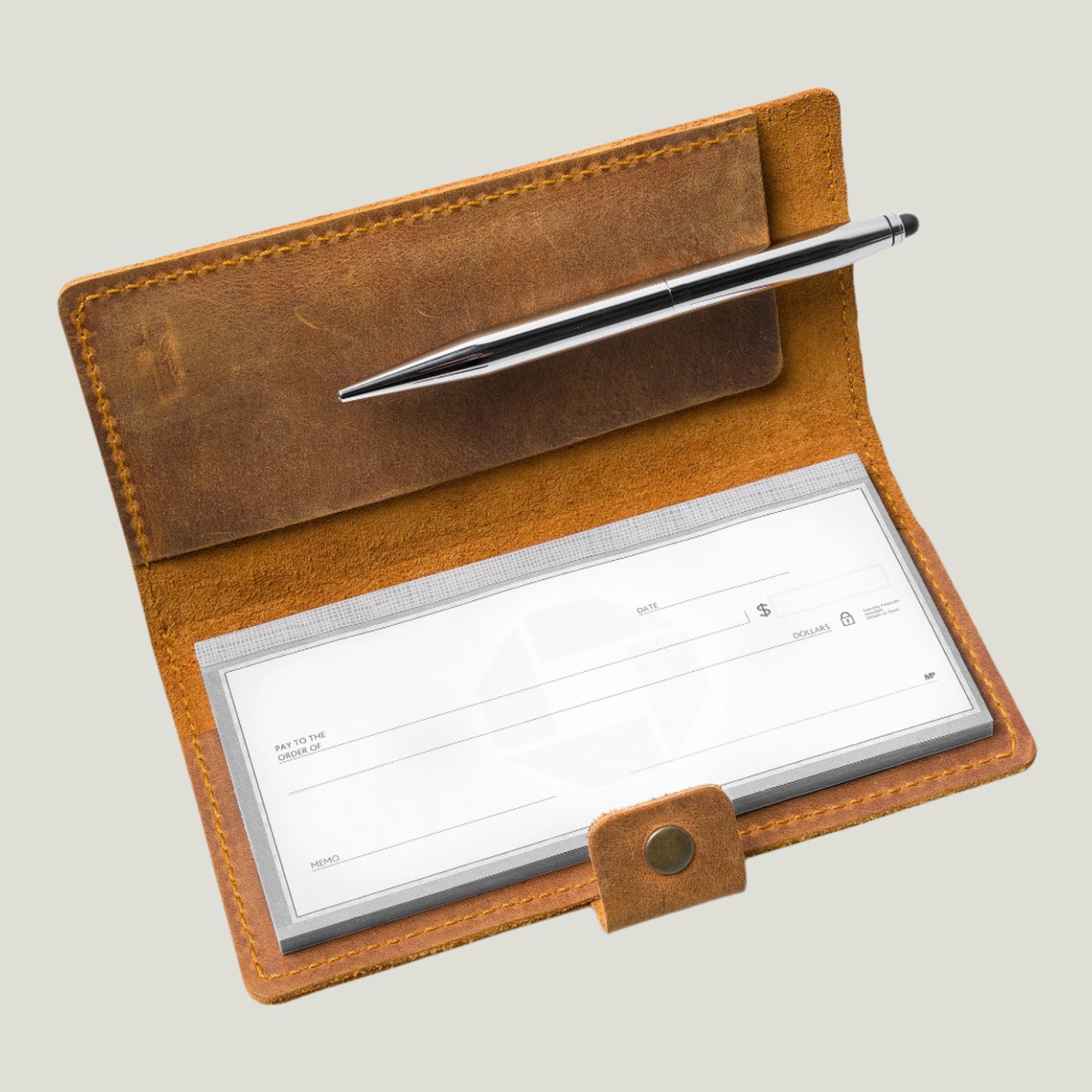 Rich cinnamon leather checkbook cover with antique brass snap closure, handcrafted by Atelier PEGAI. Personalizable with fire-branded initials, designed for standard top-tear checkbooks with an extra pocket for essentials. A timeless piece, expertly crafted in Ubrique, Spain.