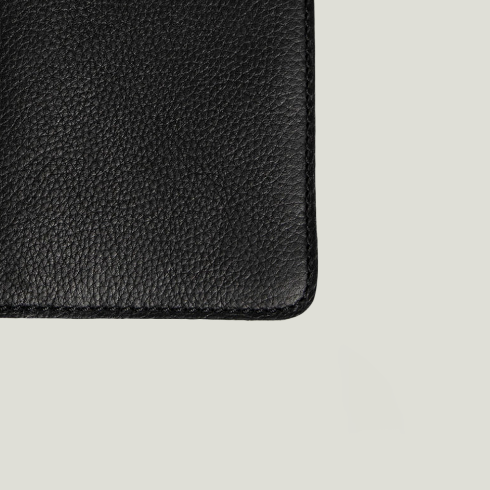 Close-up of a black leather passport holder showing its pebbled texture.