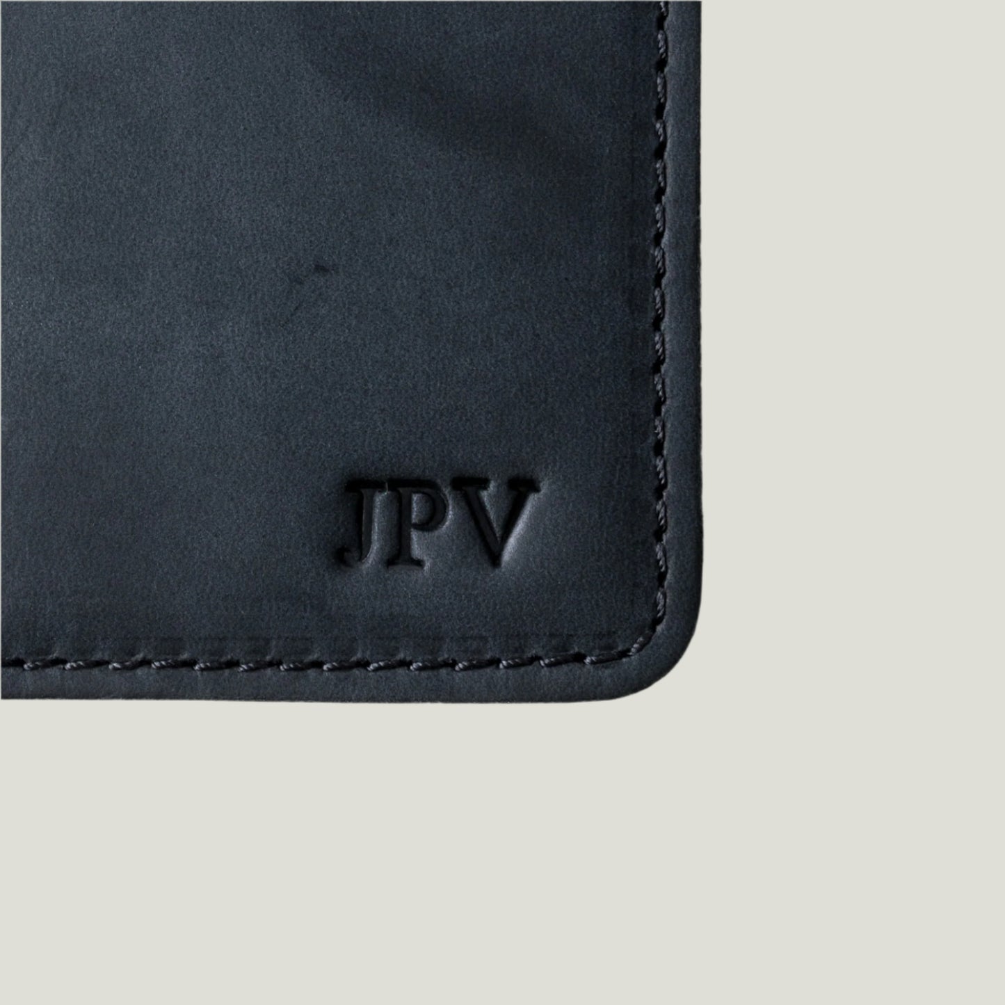 Close-up of the Pike Leather Passport Wallet in Charcoal, handcrafted from premium leather, featuring card slots, a hidden pocket, and fire-branded initials.