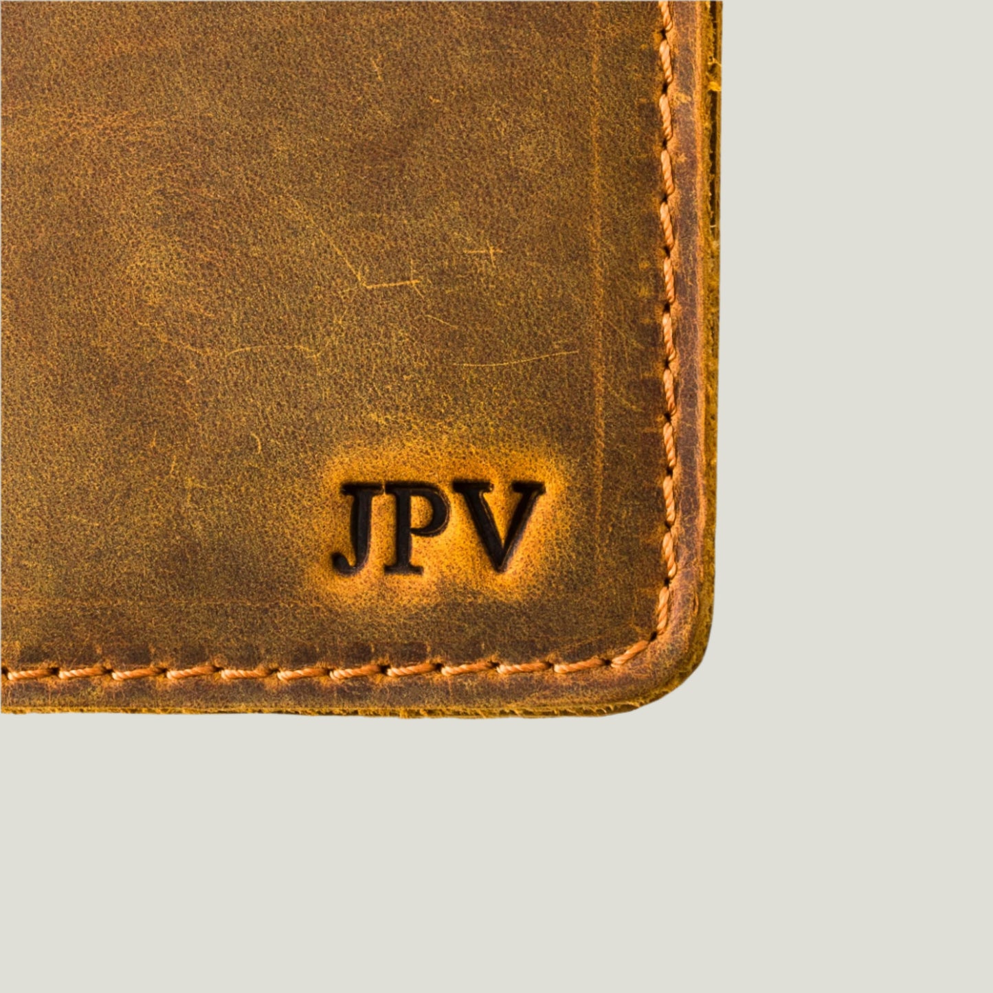 Close-up of the Pike Passport Wallet in rich Cinnamon leather, handcrafted by Atelier PEGAI, with personalized initials fire-branded on the cover.
