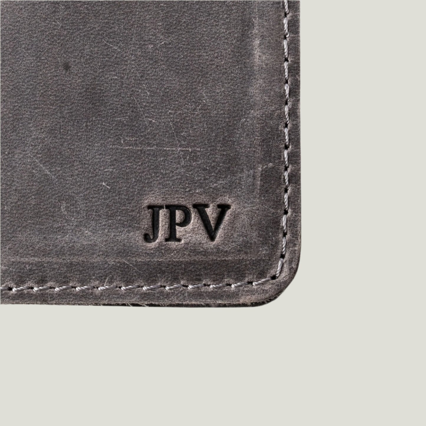 Close-up of the Pike Leather Passport Wallet in Rock, showcasing premium craftsmanship, four card slots, a hidden pocket, and fire-branded personalized initials.