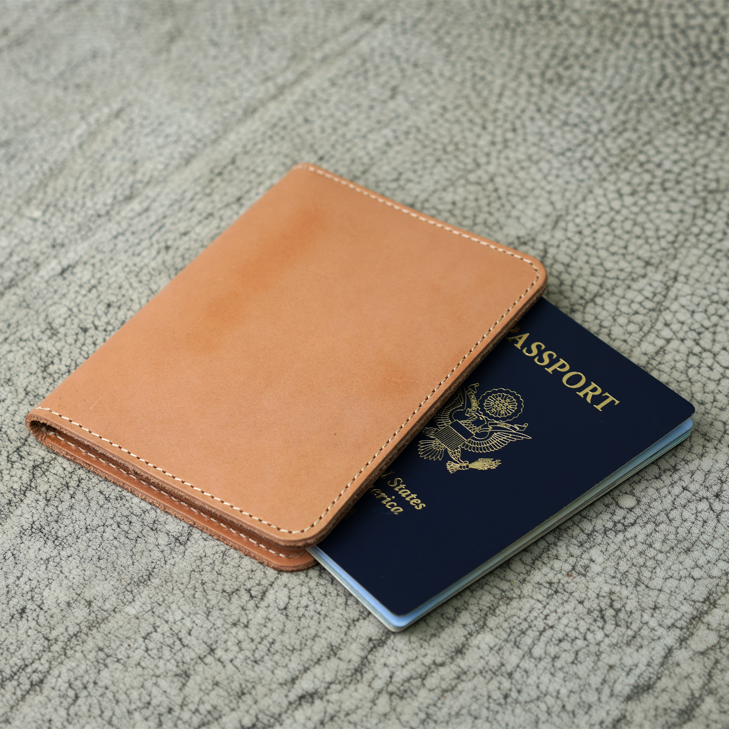 The Pike Leather Passport Wallet in Vachetta Naturale, featuring buttery smooth, light tan leather and natural white stitching. Shown partially open with a U.S. passport tucked inside, this handcrafted piece reflects raw elegance and a journey just beginning.