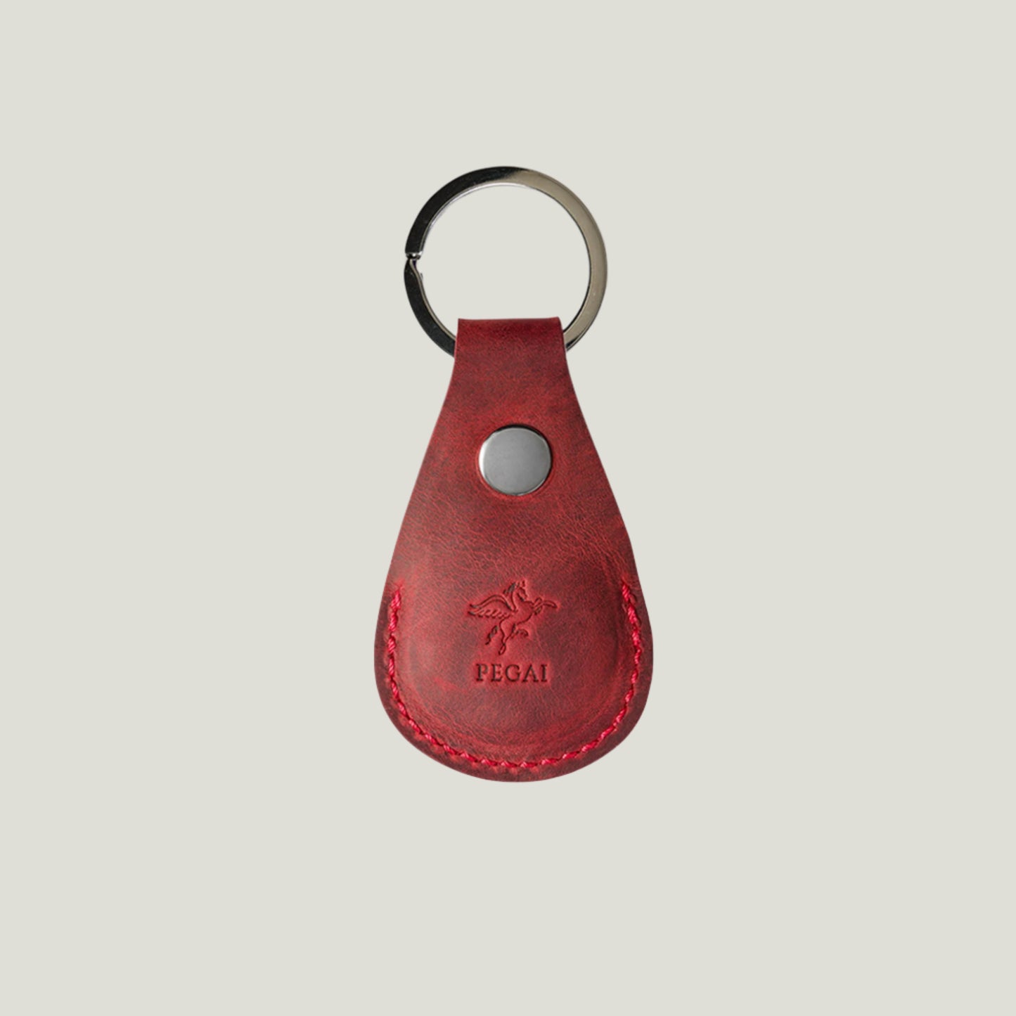 Rose-colored Pear Leather AirTag Holder by Atelier PEGAI, crafted in Spain with premium leather, featuring a snap closure and nickel hardware for secure tracking.