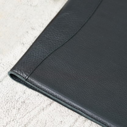 Close-up of the Marshall Padfolio in Dymnos Black, highlighting the rich texture and subtle grain of full-grain leather with tight, hand-stitched detail. A refined blend of craftsmanship and durability from Atelier PEGAI.