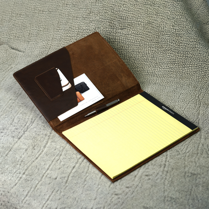 Marshall Leather Legal Padfolio in Dymnos Brown, open to reveal a pen holder, angled business card pocket, and spacious A4 document sleeve with a yellow legal pad. Made from full-grain leather and crafted with purpose—designed to keep essentials organized and your mindset sharp.