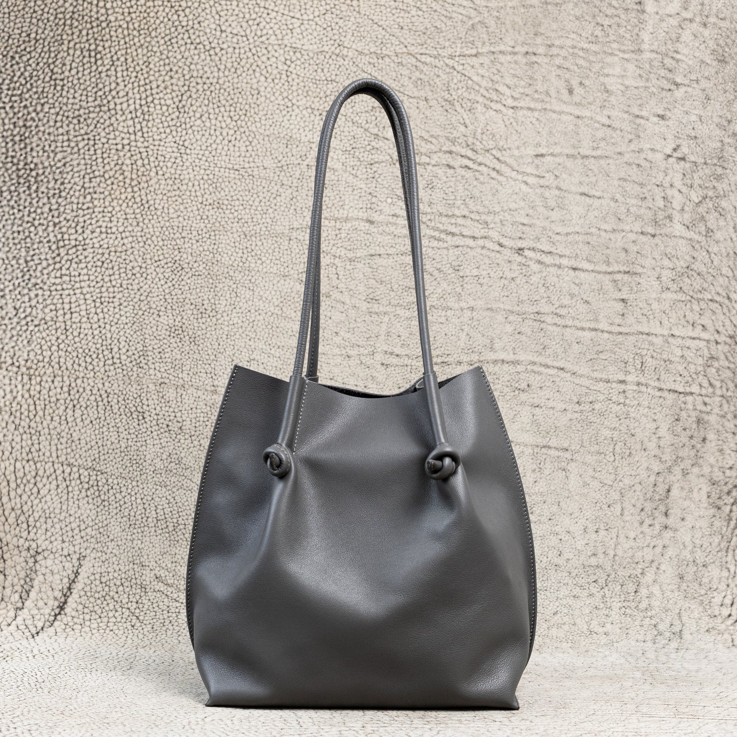 Flora Leather Tote in Silky Calf Gray with raw suede interior, rolled handles, and folded edge detailing—crafted for everyday ease and timeless charm.