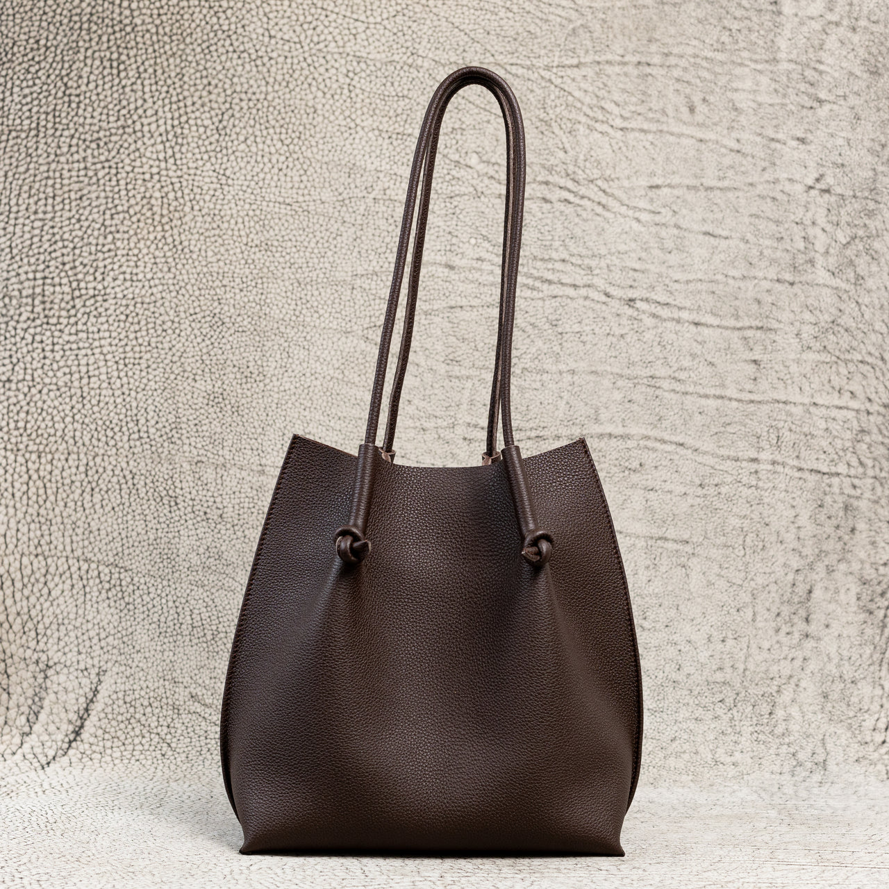 Flora Everyday Leather Tote in Togo Calf Brown with raw suede interior, rolled handles, and folded edge details—crafted for timeless, daily use.