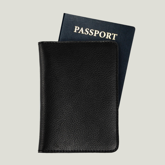 A black leather passport holder with a navy passport partially tucked inside.
