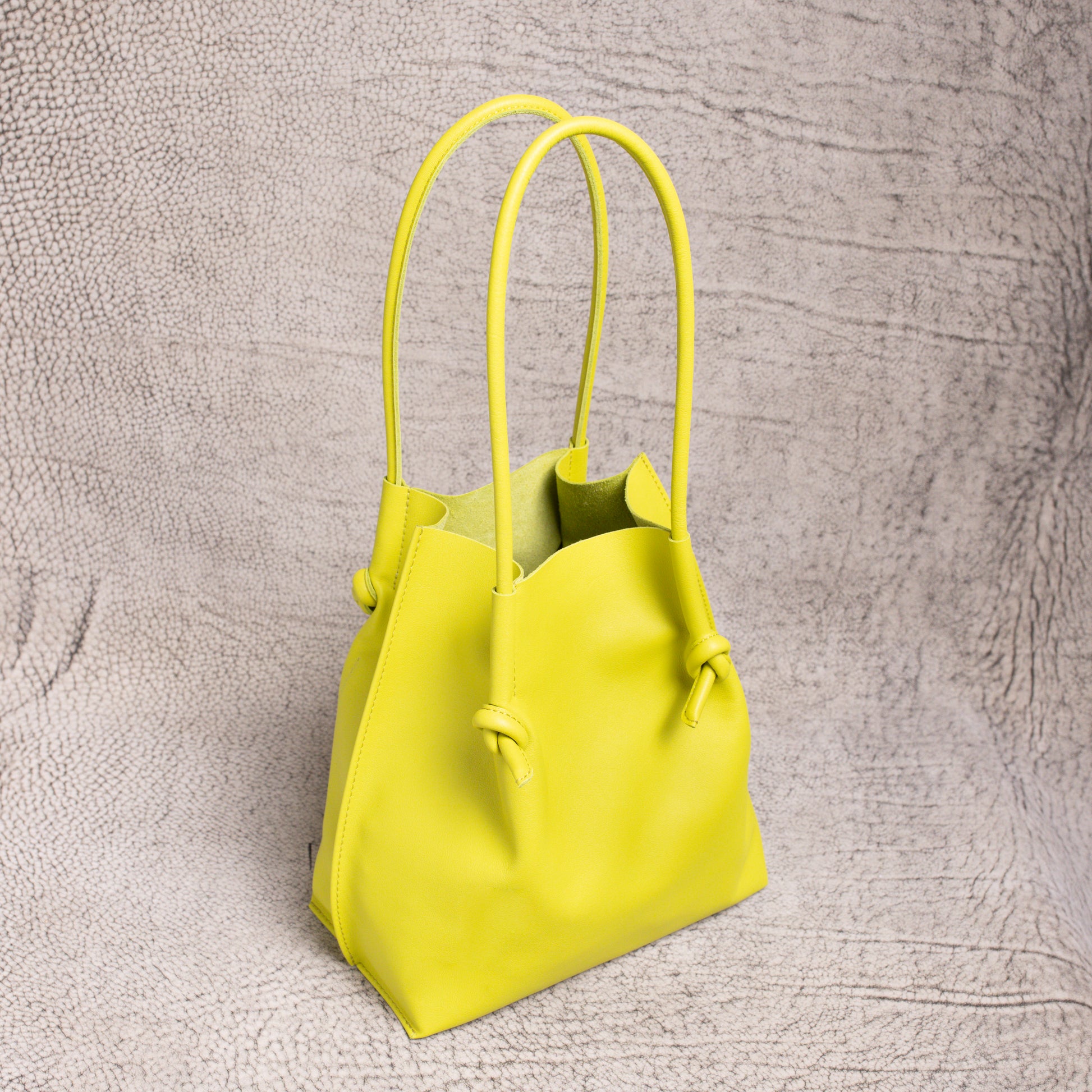 Angled view of the Flora Leather Tote highlighting its spacious open-top and raw suede interior in vibrant lime leather.