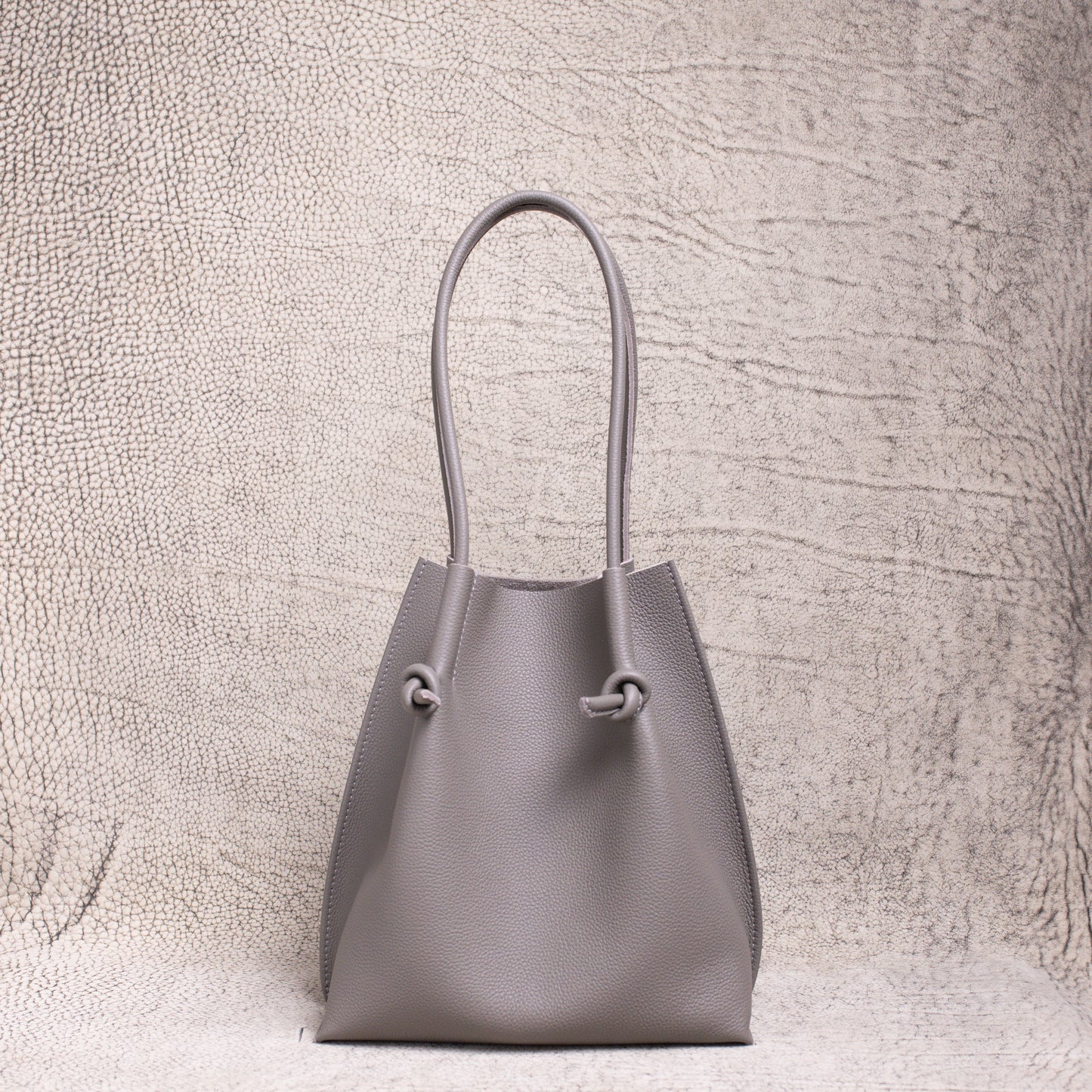Front-facing view of the Flora Everyday Tote in Togo Gris, showing its softly structured form and knotted leather handles.