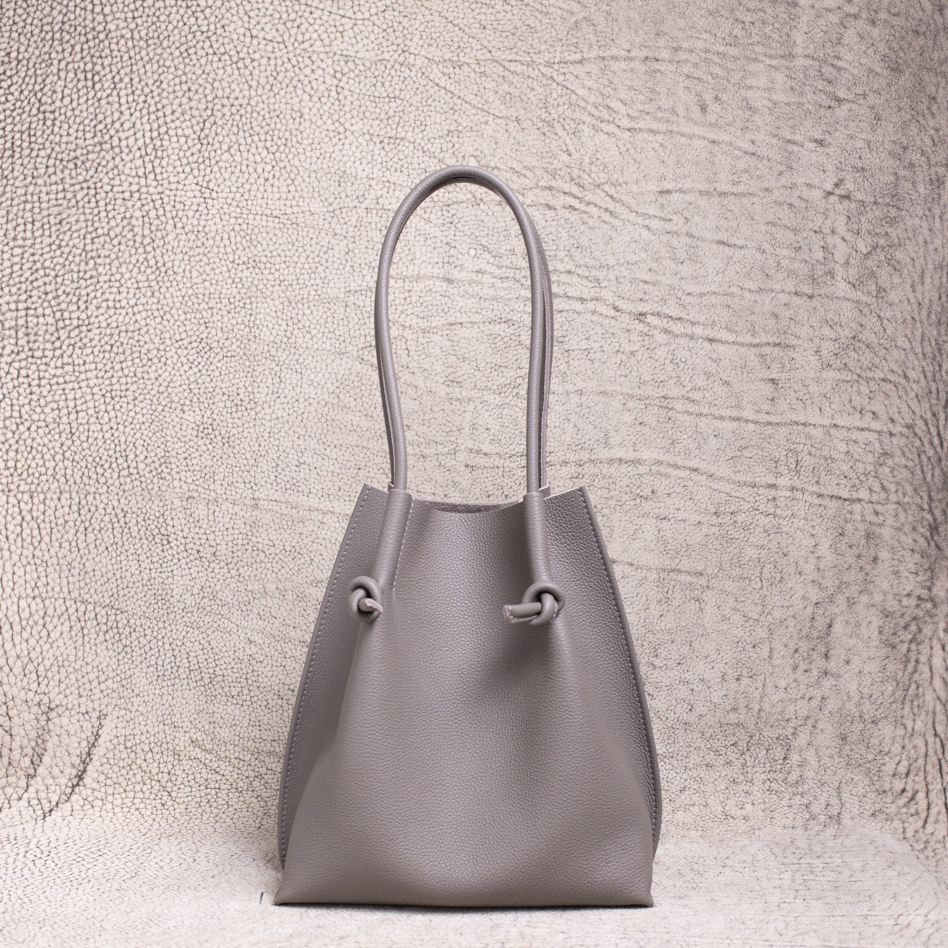 Front-facing view of the Flora Everyday Tote in Togo Gris, showing its softly structured form and knotted leather handles.