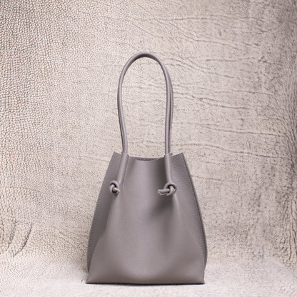 Front-facing view of the Flora Everyday Tote in Togo Gris, showing its softly structured form and knotted leather handles.
