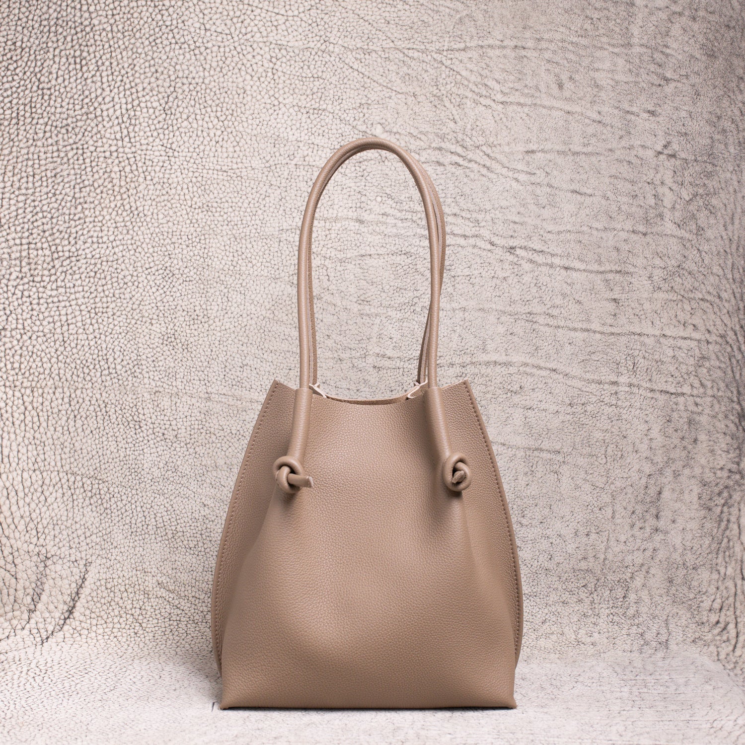 Front view of the Flora Tote in Togo Etoupe leather, displaying its structured silhouette and soft pebbled texture.