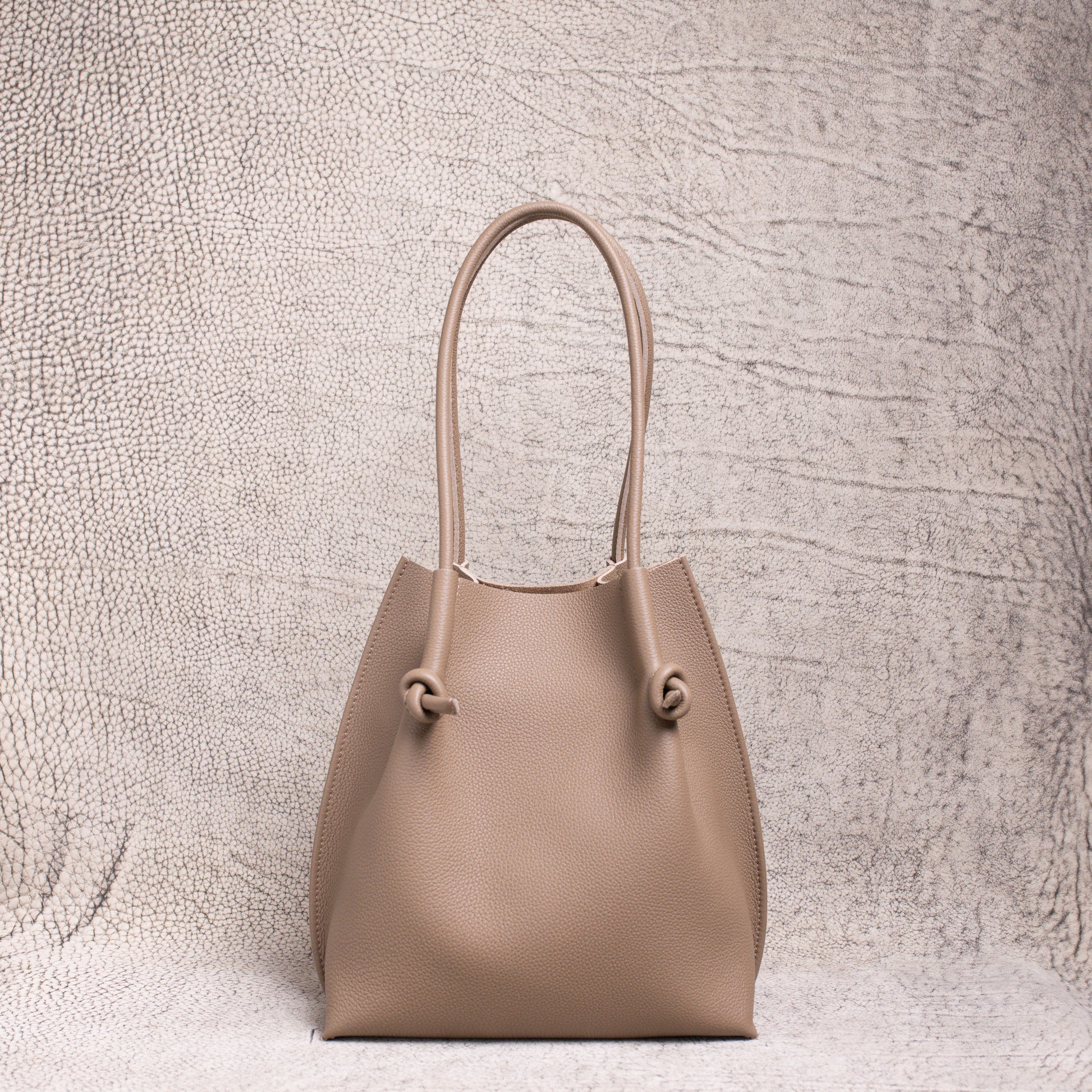 Front view of the Flora Tote in Togo Etoupe leather, displaying its structured silhouette and soft pebbled texture.