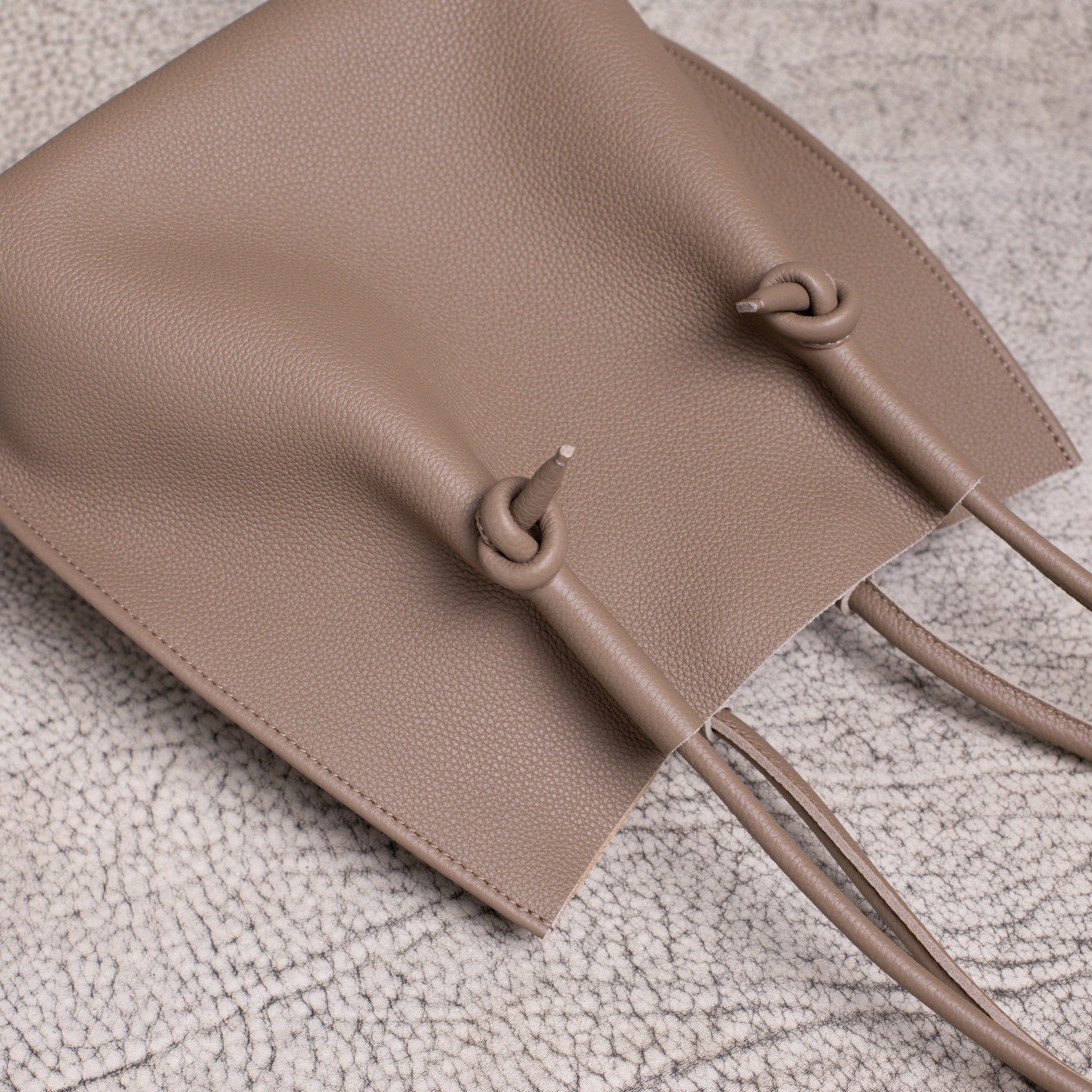Overhead flat lay showing the top handles and relaxed body of the Flora Tote in warm Etoupe calfskin.