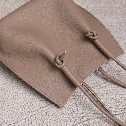 Overhead flat lay showing the top handles and relaxed body of the Flora Tote in warm Etoupe calfskin.