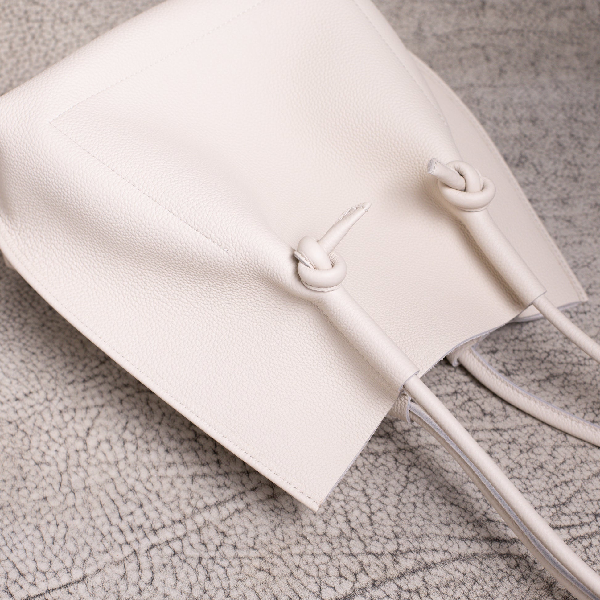Overhead close-up showing the knotted handle design and subtle grain of the Beige Togo leather.
