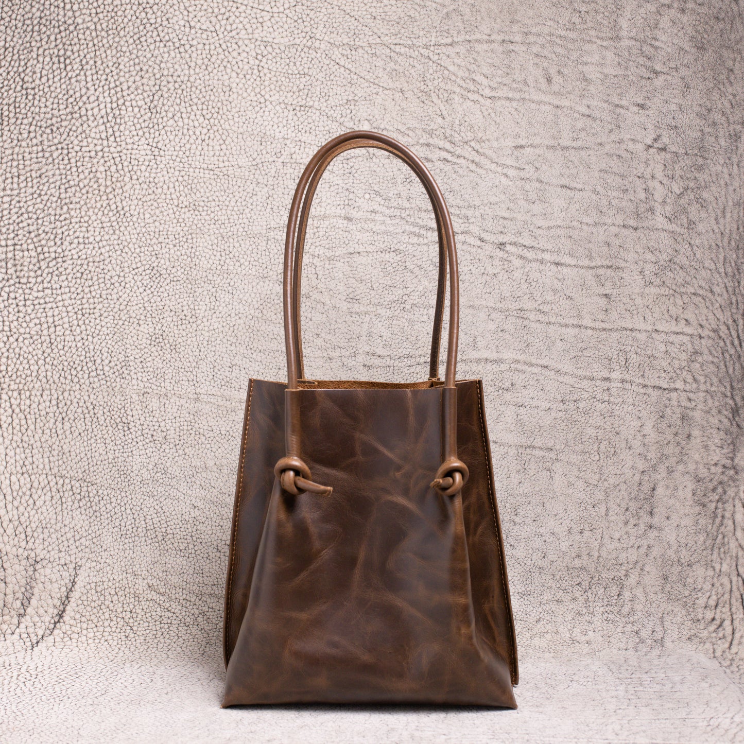 Front view of the Flora Everyday Leather Tote in dual-tone coffee, showcasing its knotted rolled handles and rich artisan leather finish.