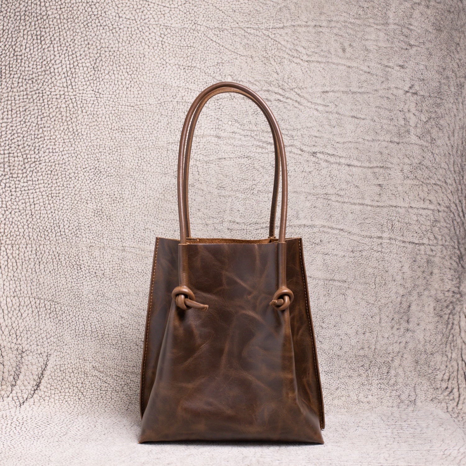 Front view of the Flora Everyday Leather Tote in dual-tone coffee, showcasing its knotted rolled handles and rich artisan leather finish.