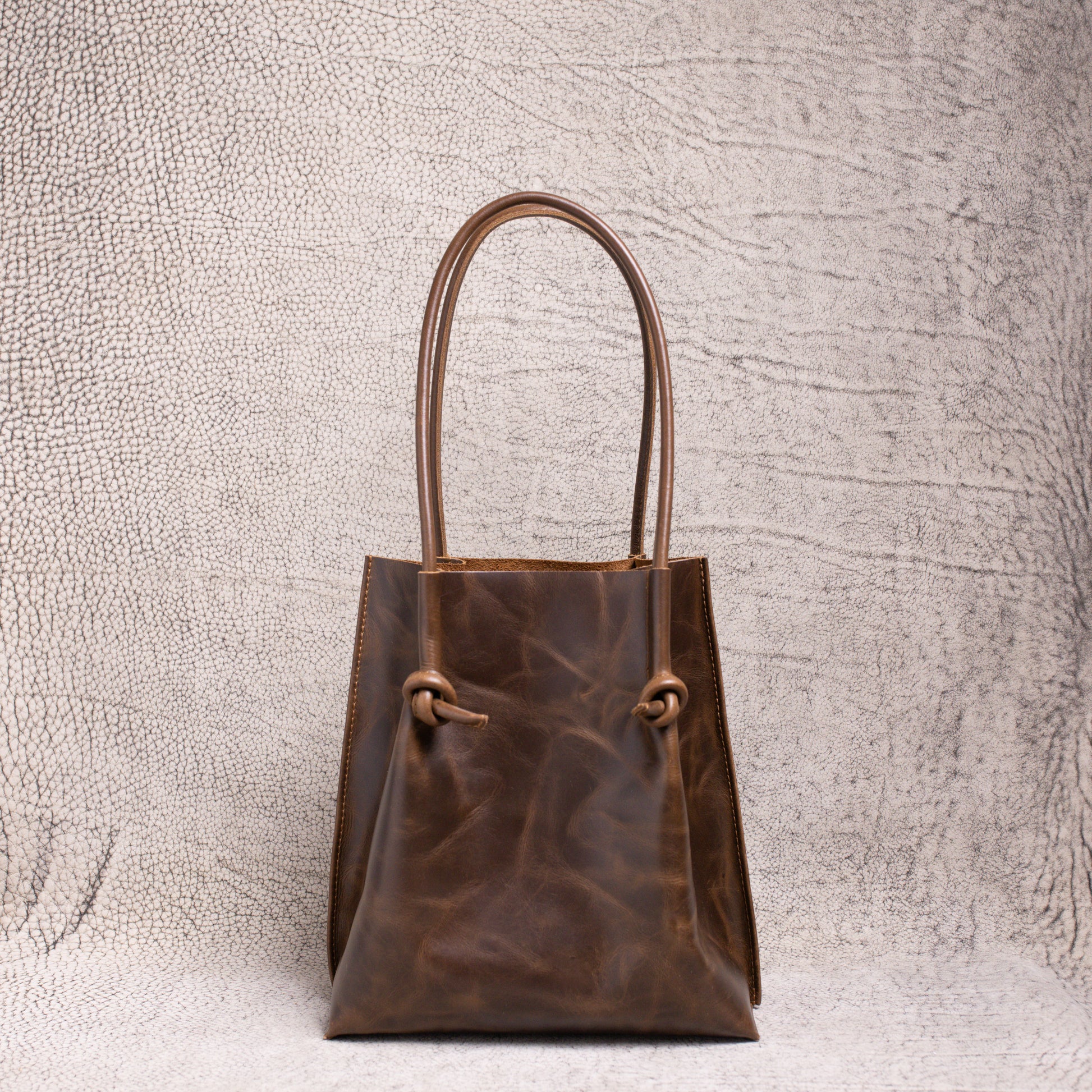 Front view of the Flora Everyday Leather Tote in dual-tone coffee, showcasing its knotted rolled handles and rich artisan leather finish.