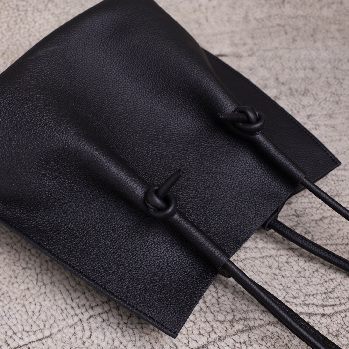 Flat lay of the tote from above, displaying its relaxed structure, signature knotted handles, and soft leather drape.