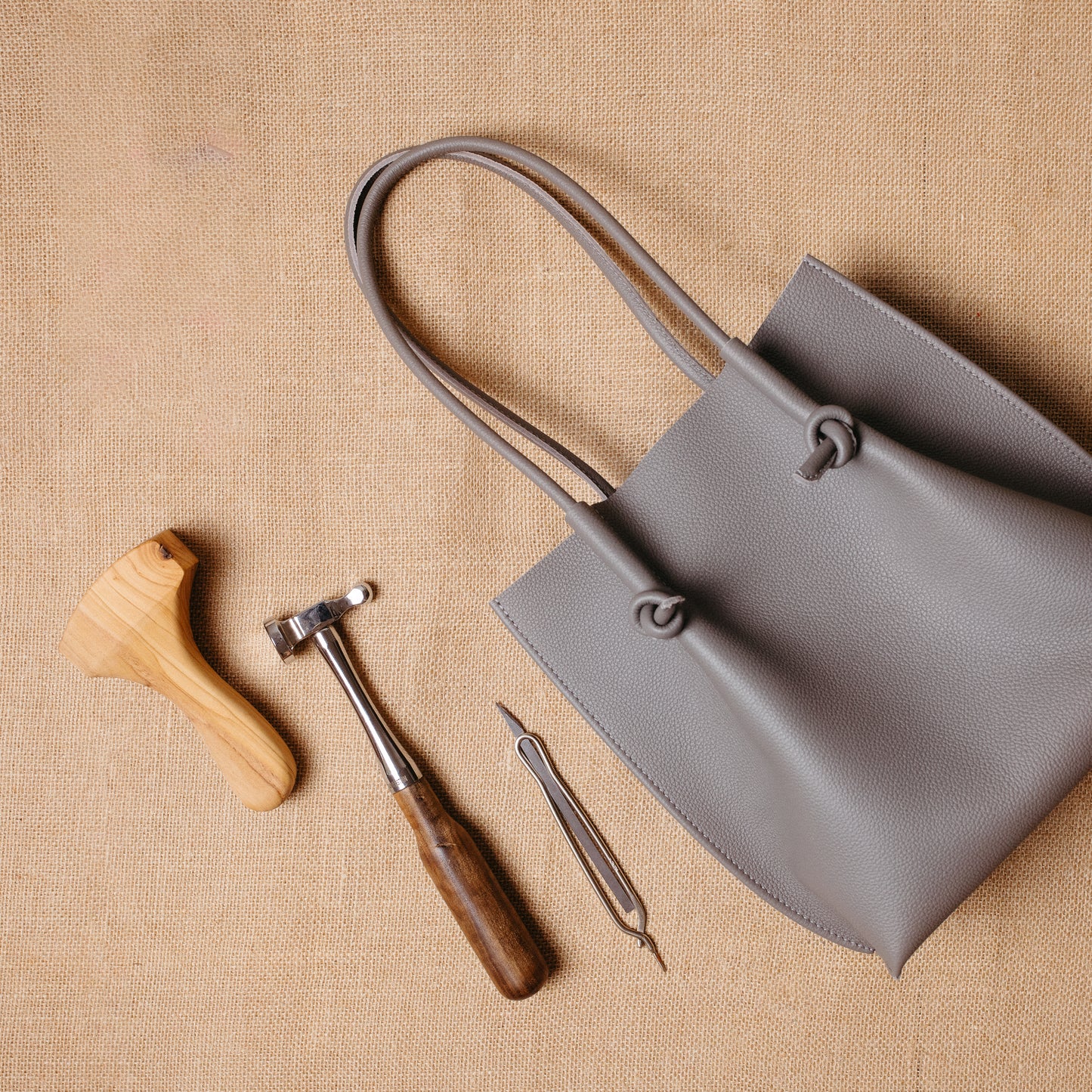 Flora tote placed beside traditional leather tools on a natural fabric surface—highlighting the artisanal craftsmanship behind the bag.