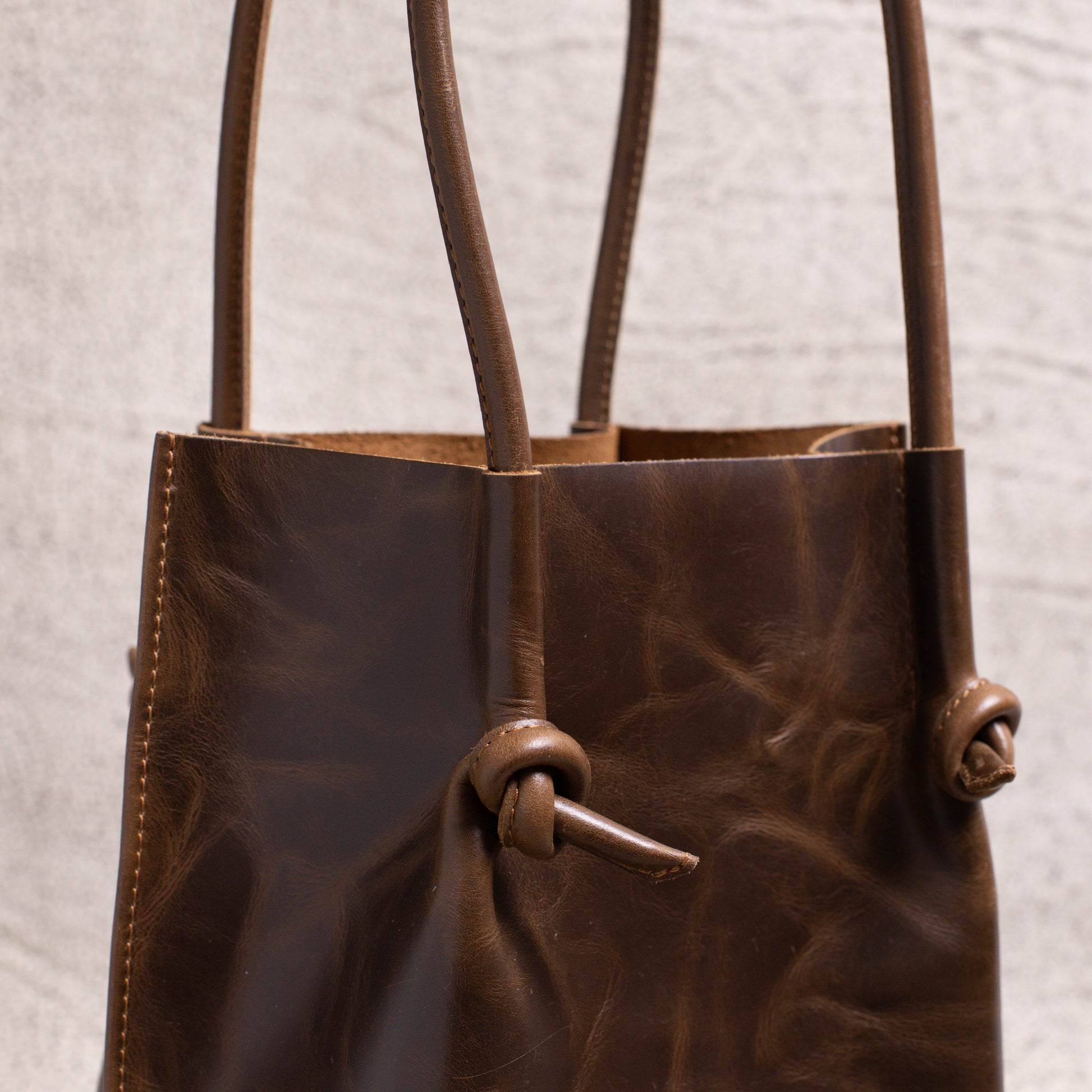 Detailed view of the tote's knotted handles and folded-edge construction, emphasizing durability and refined craftsmanship.