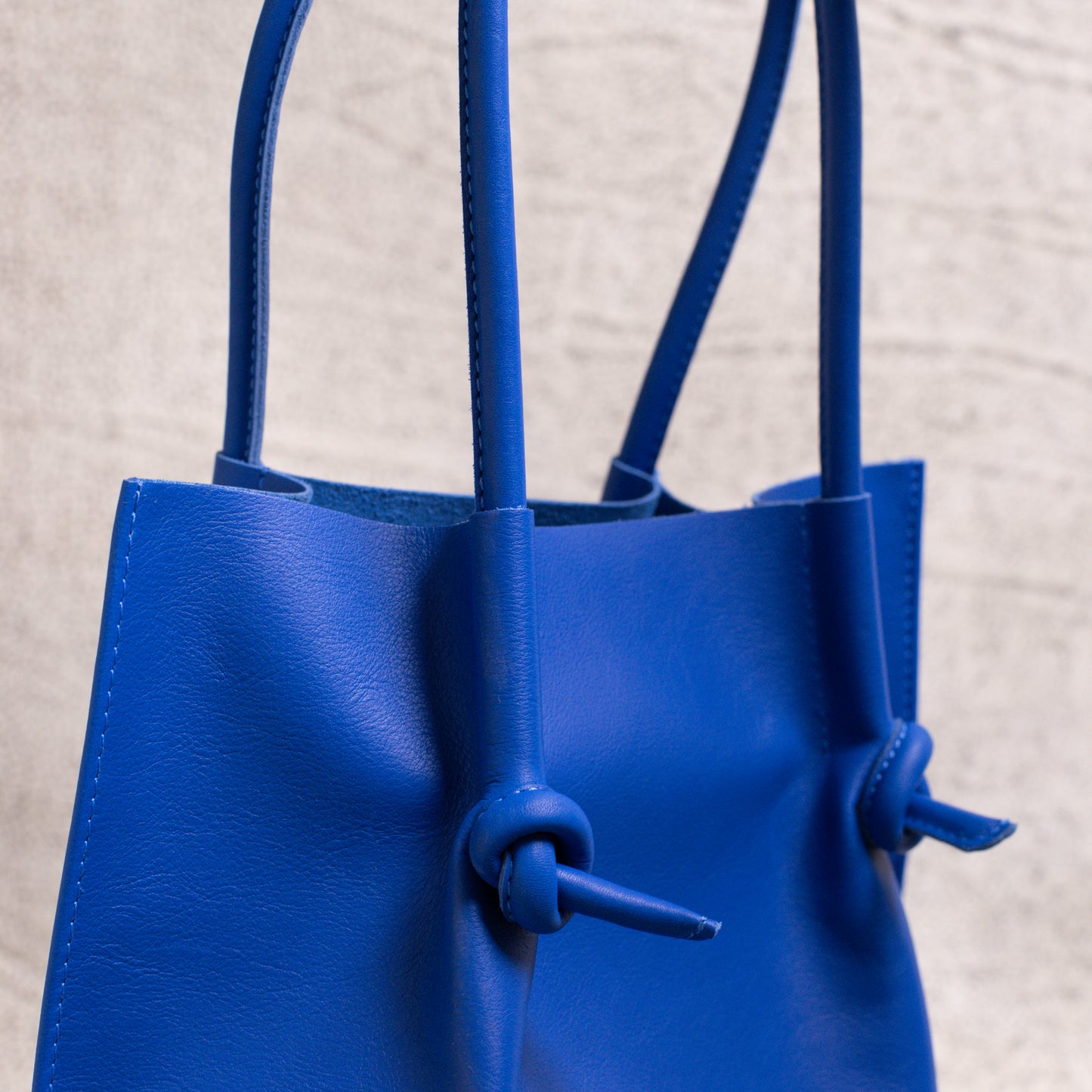 Detailed shot of the tote’s rolled leather handles and folded edge, showcasing its durability, construction, and refined finish.