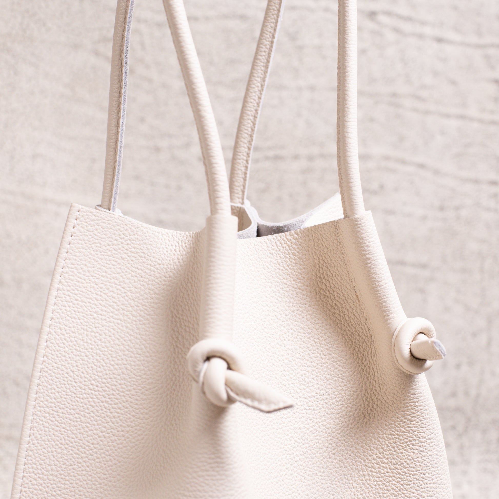 Tight shot of the dual handles and edge stitching on the Flora Tote in Beige.