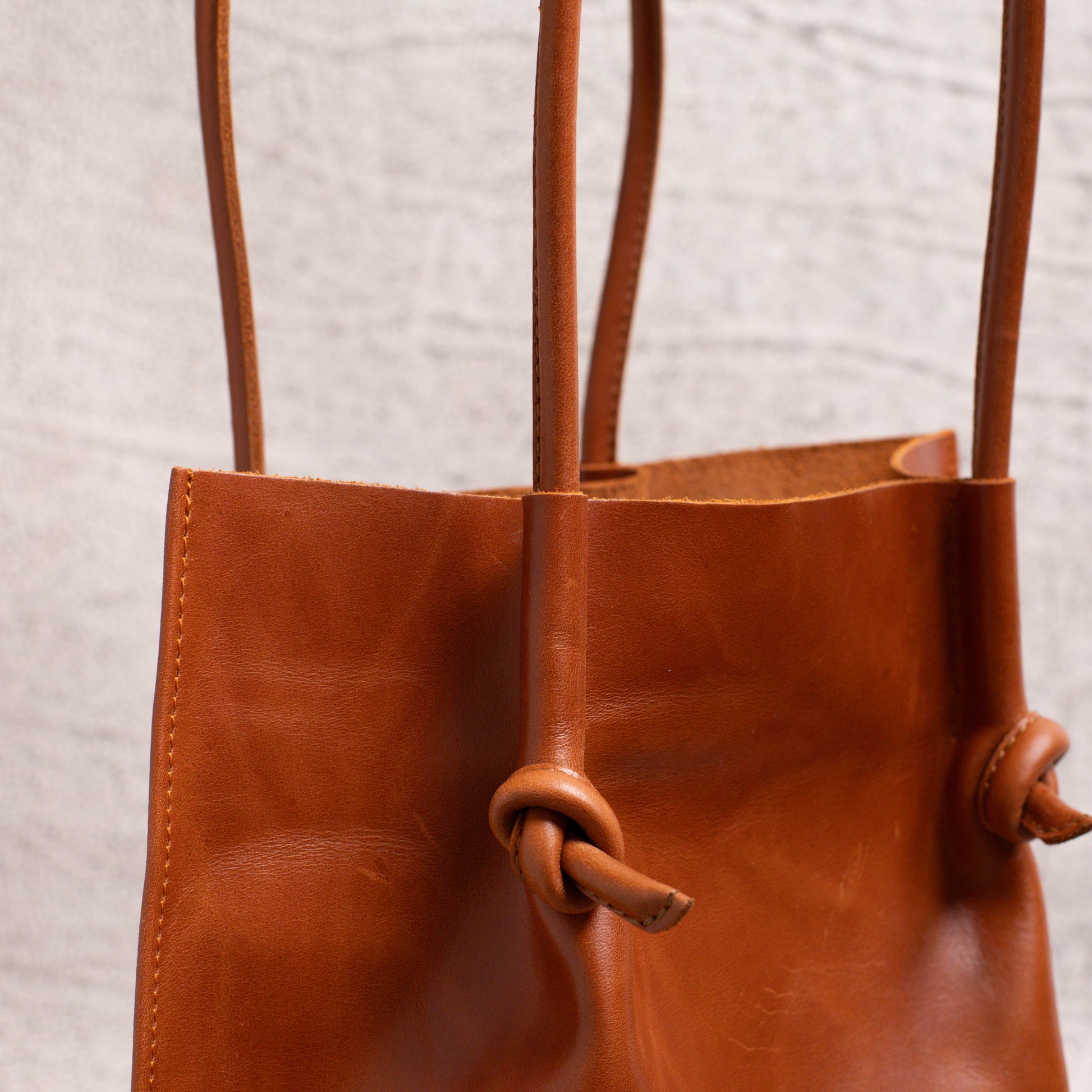 Detailed shot of the knotted handle and folded edge stitching on the Flora Leather Tote, emphasizing fine craftsmanship and structure.