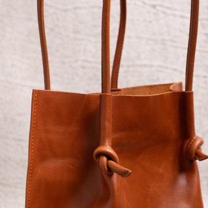 Detailed shot of the knotted handle and folded edge stitching on the Flora Leather Tote, emphasizing fine craftsmanship and structure.