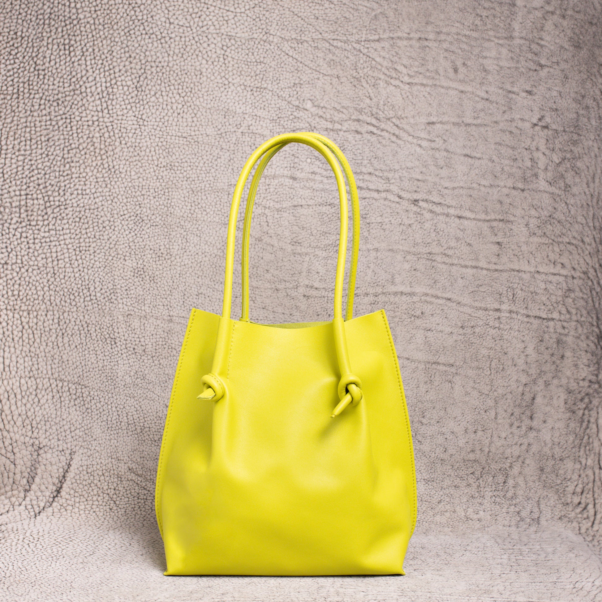 Front view of the Flora Everyday Leather Tote in Silky Calf Lime, showing its minimal design, knotted handles, and smooth leather finish.