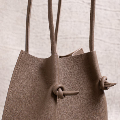 Side detail close-up showing the folded seam, dual handles, and signature knotted leather accents of the Etoupe edition.