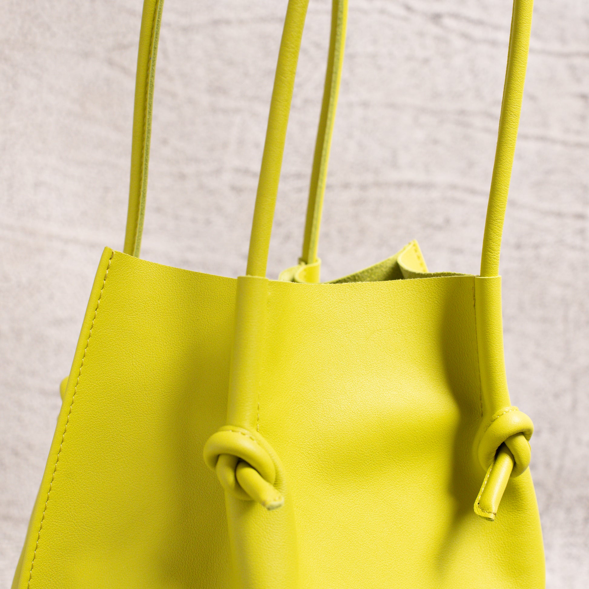 Detailed view of the dual-rolled leather handles and top edge of the Flora Tote, emphasizing the soft texture and construction quality.