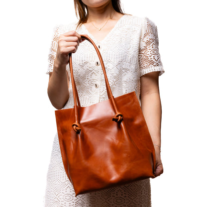 A woman holding the Flora Everyday Leather Tote by the handles, showing its real-life scale and how it complements an elegant outfit.