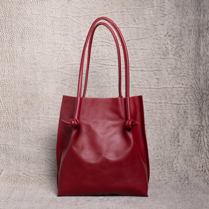 Front-facing view of the Flora Leather Tote in Smooth Calf Burgundy, showcasing its rich artisan leather, dual rolled handles, and minimalist knot detailing.