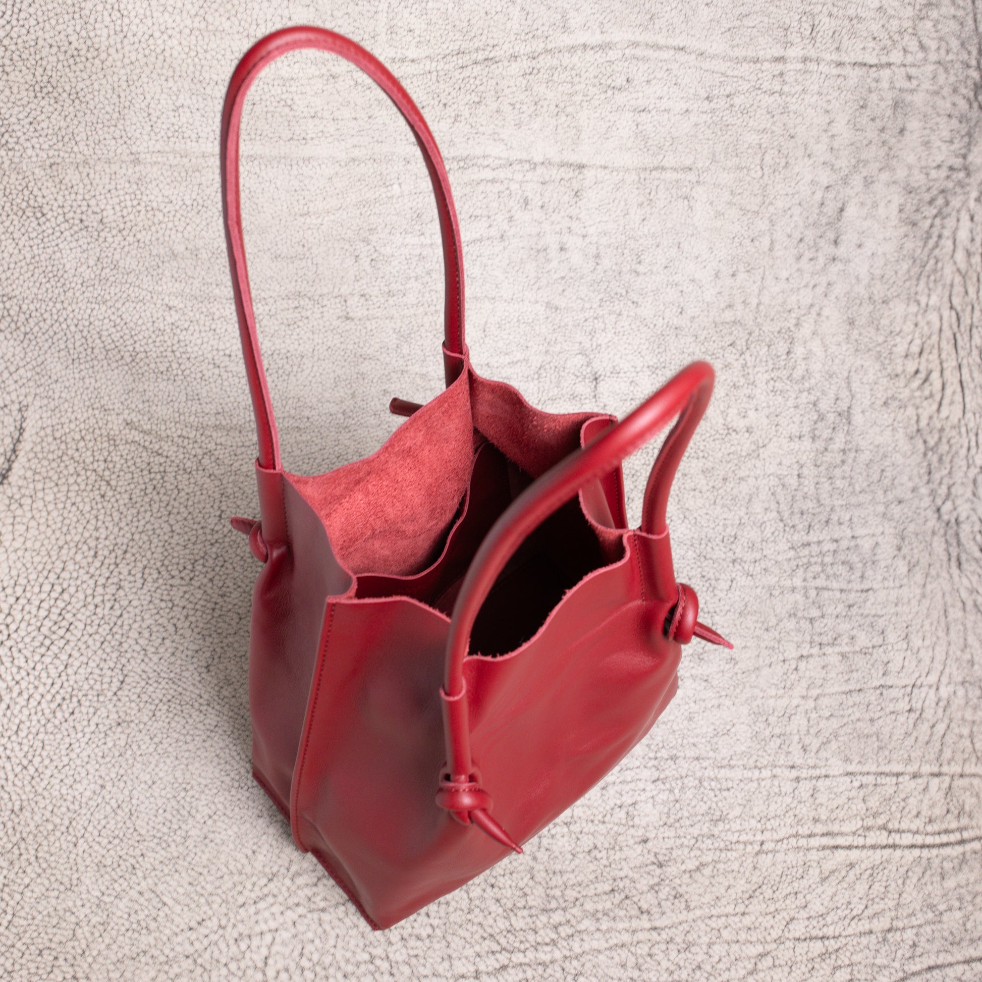 Top-down view into the Flora Leather Tote in Smooth Calf Burgundy, revealing the raw suede interior and side pocket for organizing essentials.