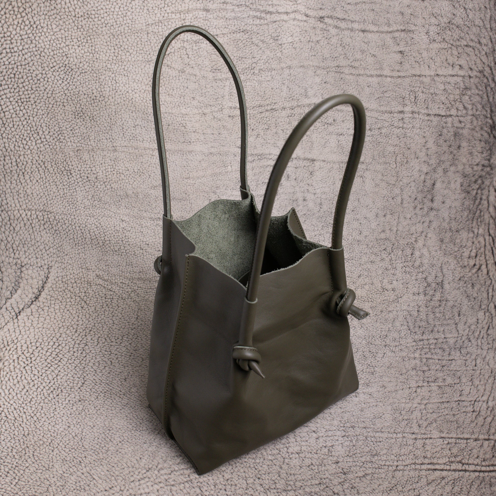 Top-down look inside the Flora Leather Tote in Smooth Calf Green, revealing its raw suede interior and spacious, open-top design.