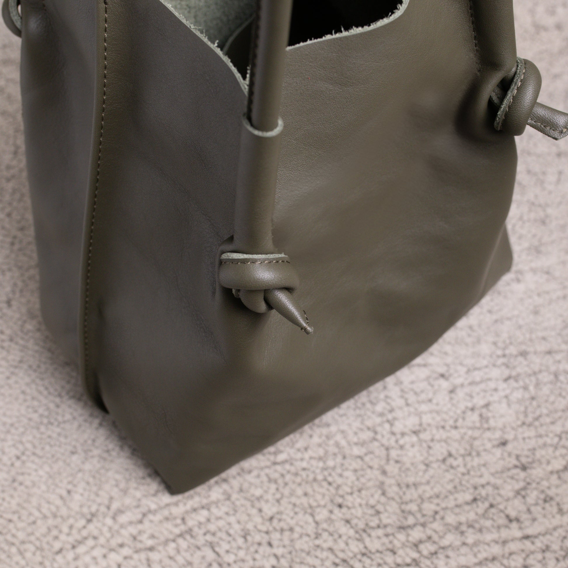 Close-up of the bottom corner of the Flora Tote in Smooth Calf Green, focusing on reinforced stitching and knotwork for lasting durability.