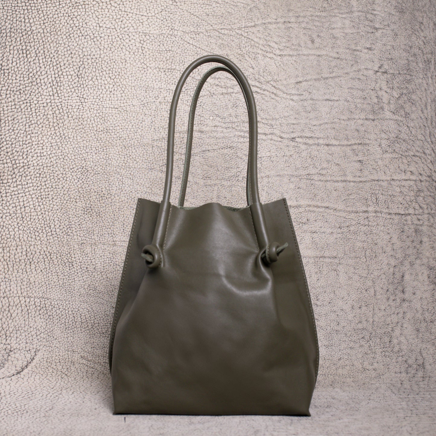 Front view of the Flora Leather Tote in Smooth Calf Green, featuring minimalist knotted handles and clean, structured artisan leather.