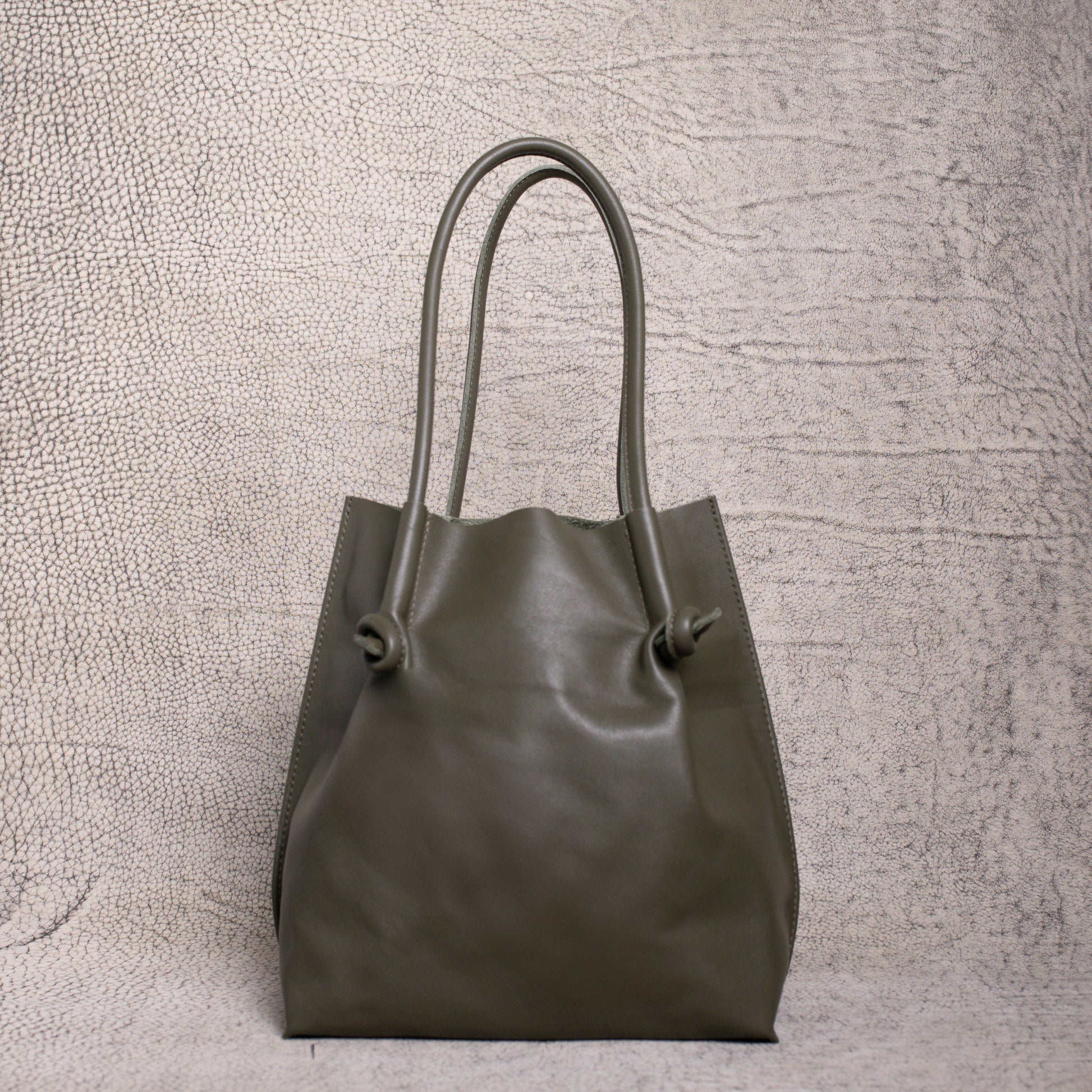 Front view of the Flora Leather Tote in Smooth Calf Green, featuring minimalist knotted handles and clean, structured artisan leather.