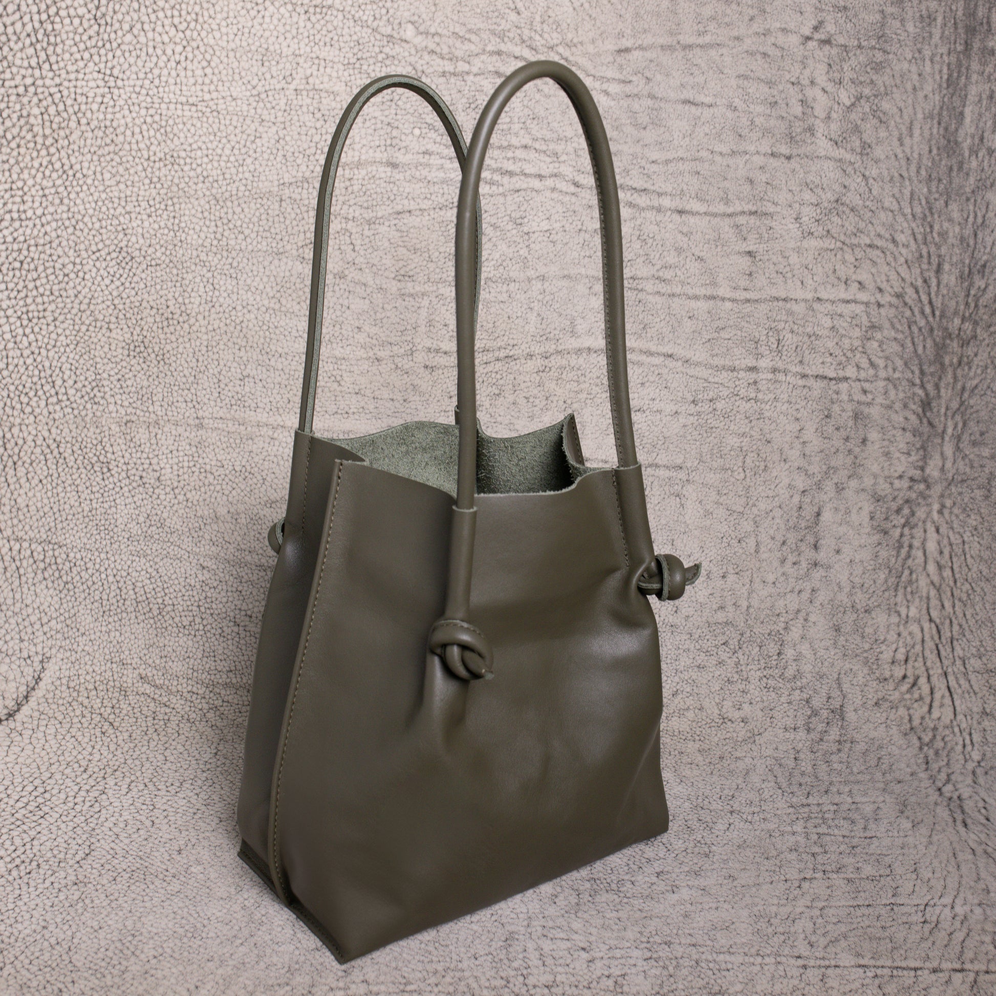 Angled side view of the Flora Tote in Smooth Calf Green, showing the soft suede interior and sculpted silhouette that blends style with utility.
