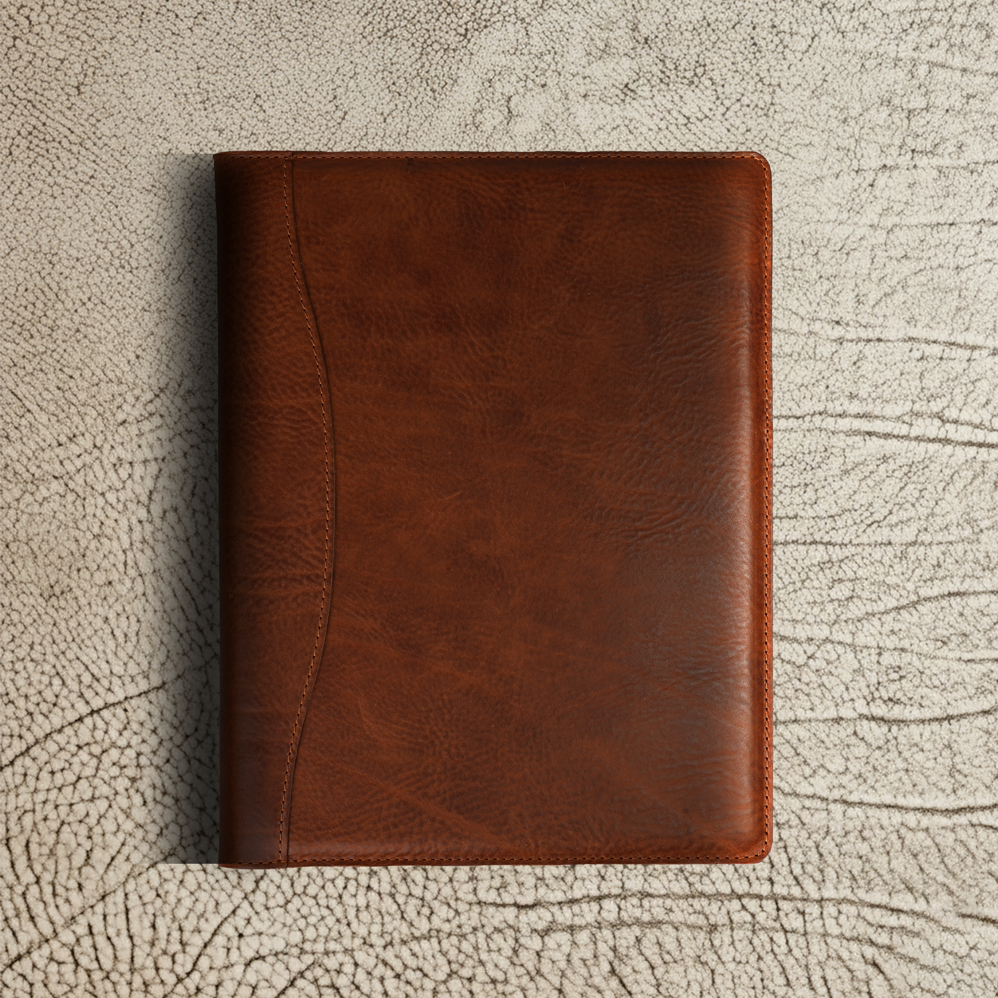 Marshall Leather Legal Padfolio in Missouri Dark Brown, shown closed on a textured surface. The rich full-grain leather features natural grain patterns and a minimalist silhouette—crafted for professionals who lead with purpose, not noise.