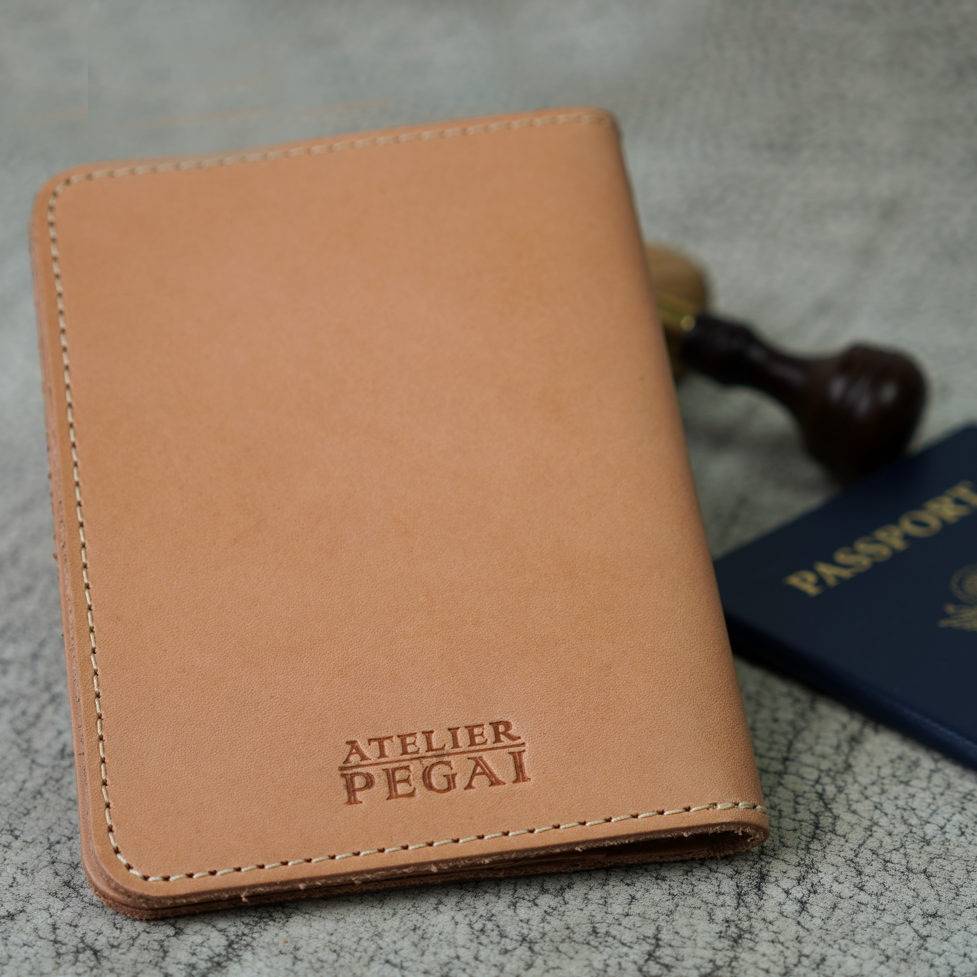 Close-up of the Vachetta Naturale Pike Leather Passport Wallet by Atelier PEGAI, embossed with the signature logo. The undyed, full-grain leather showcases a clean, unfinished look that will darken beautifully with time—crafted to carry your story from the very first stamp.